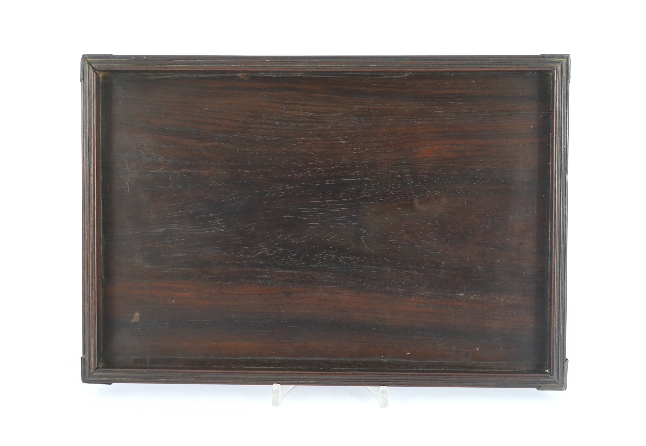 A Chinese hardwood rectangular tray, Qing dynasty, possibly Zitan, with brass mounted corners and reeded edges, 35.5cm x 23.5cm, old splits and repairs